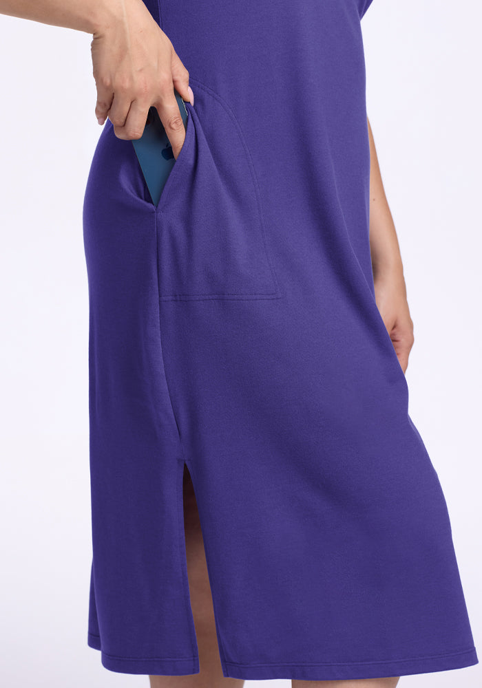 Someone slips a teal phone into the side pocket of the Woolx Cassie Dress - Berry Indigo with a small slit at the hem.