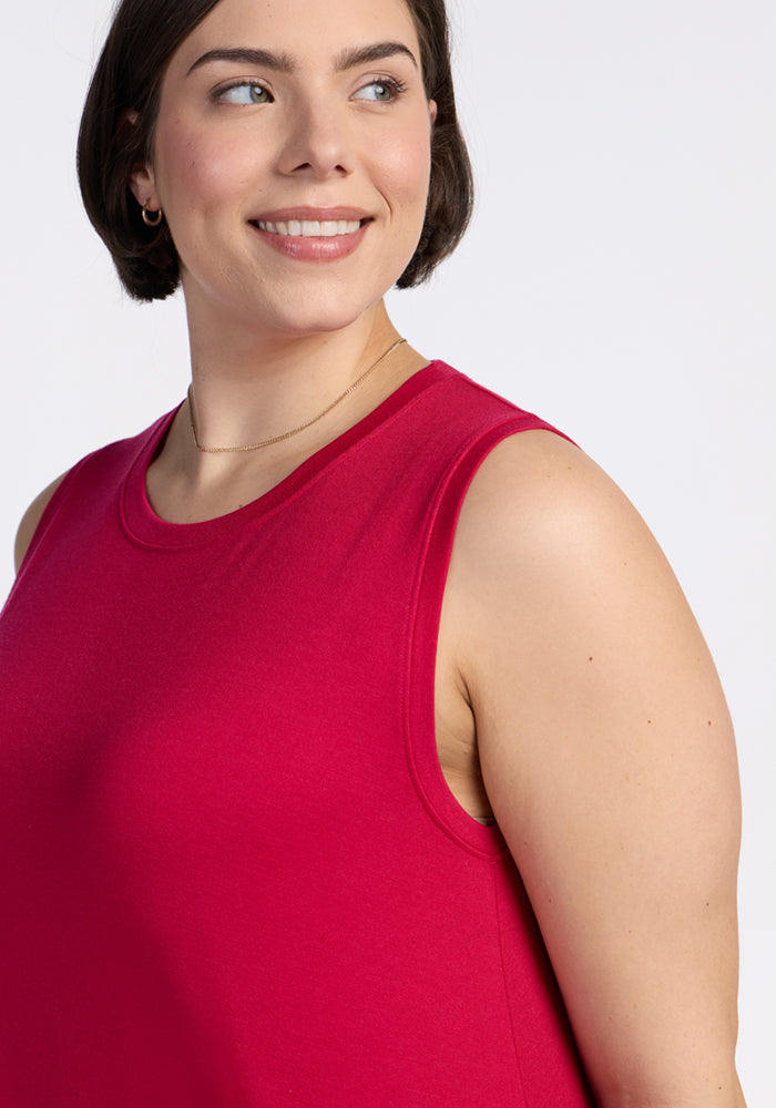 A woman with short brown hair smiles and looks to her left against a plain light background while wearing the Woolx Clara Dress in Poppy Spark.