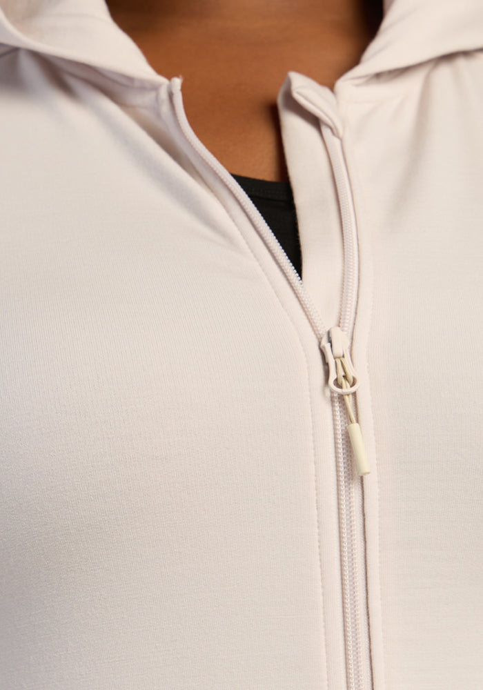 Close-up of the Woolx Darby Zip Up Hoodie in Ecru, partially unzipped to show a black shirt underneath.