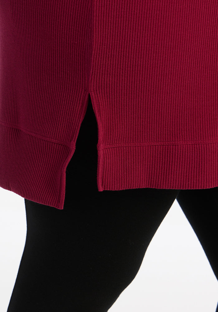 A close-up of the Woolx Evie Ribbed Tunic in Beet Red, styled over black leggings for a cozy women’s top look.