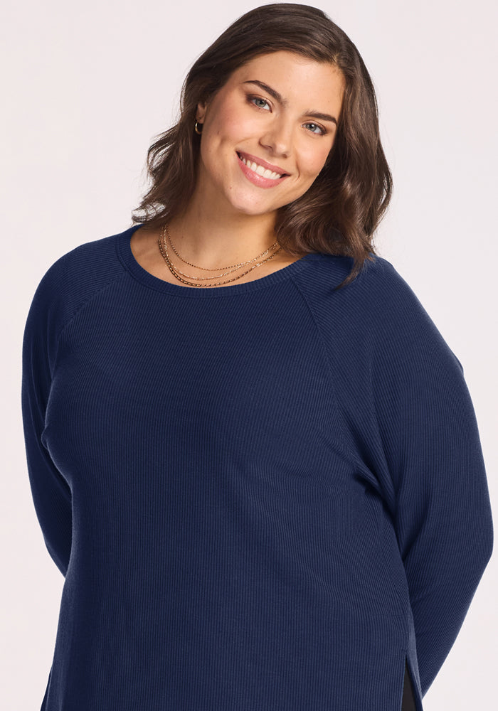 Smiling woman with wavy brown hair in Woolx Ainsley Sweater - Ocean Cavern, posed against a light background.