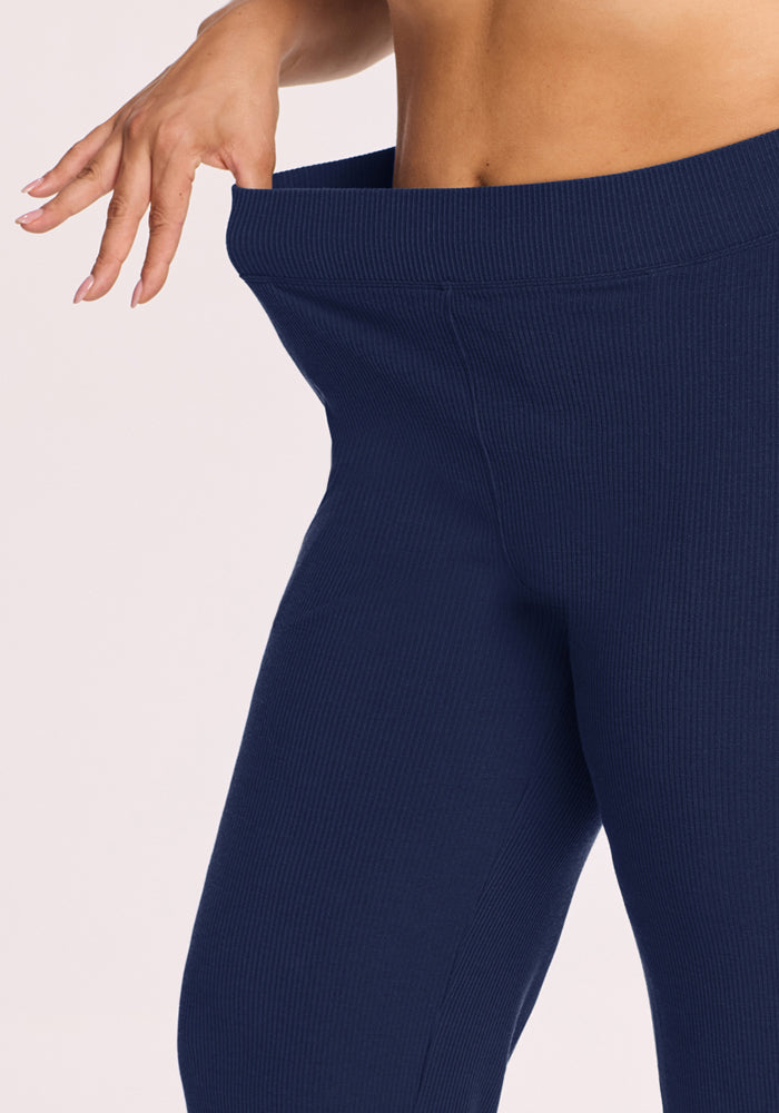 Person stretches the waistband of Woolx Luca Ribbed Pants - Ocean Cavern, showing their loose, flexible wide leg fit.