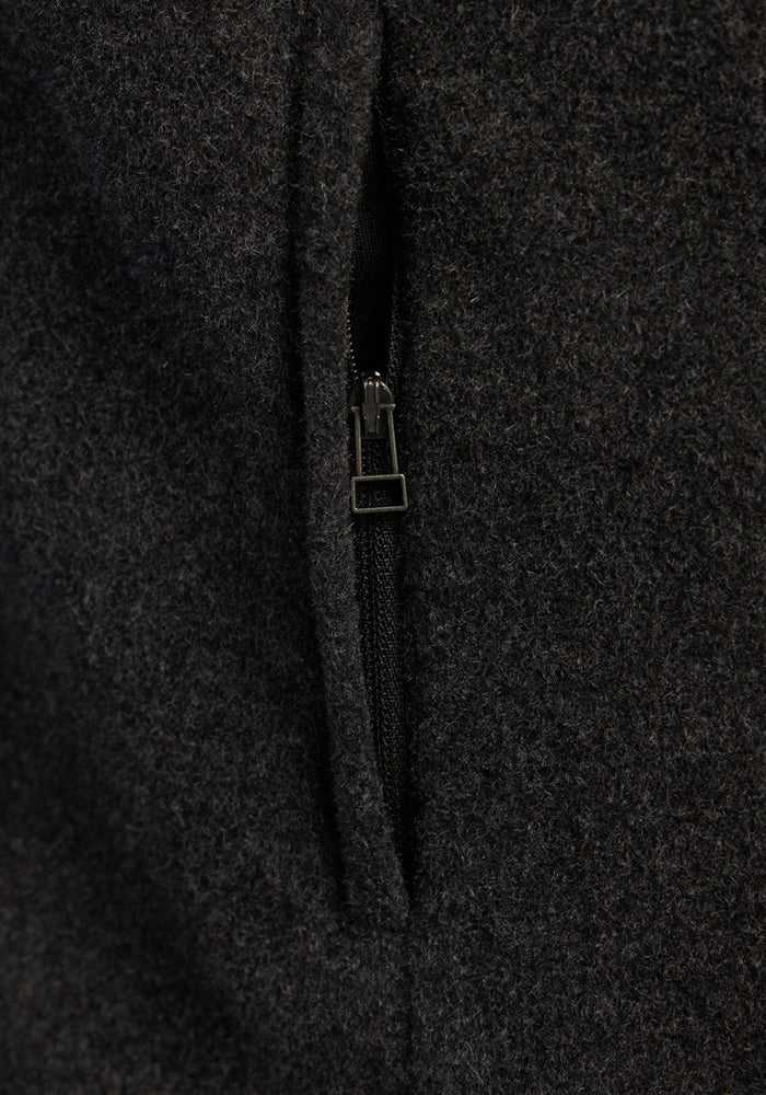 Close-up of the black zipper on the Woolx Haley Vest - Carbon Black, shown on dark textured fabric.