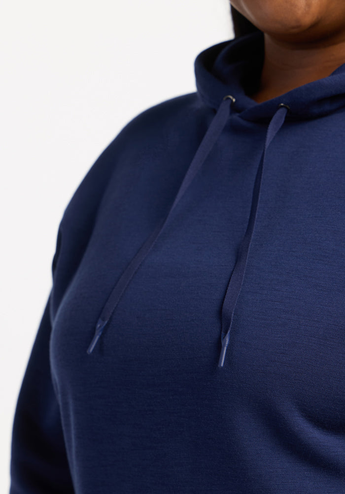 Model wears the Woolx Avery Hoodie - Ocean Cavern, a navy sweatshirt with drawstrings, against a white background.