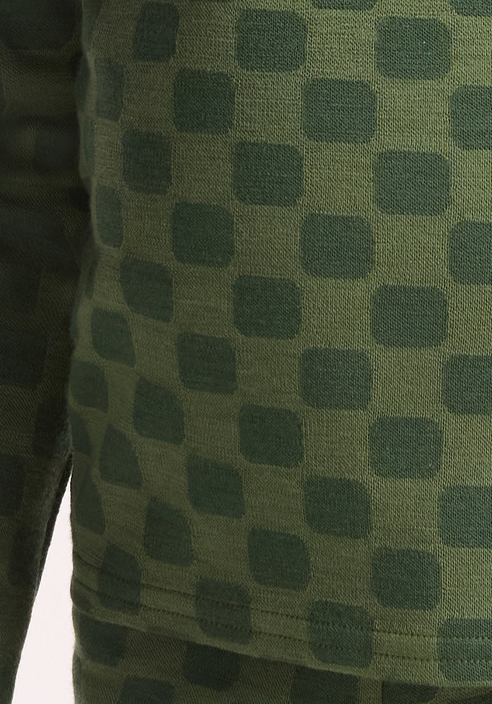 Close-up of the Woolx Kids Explorer Base Layer Top - Frog Hop: breathable green fabric with a grid of darker green rounded squares, shown as part of this children's garment.