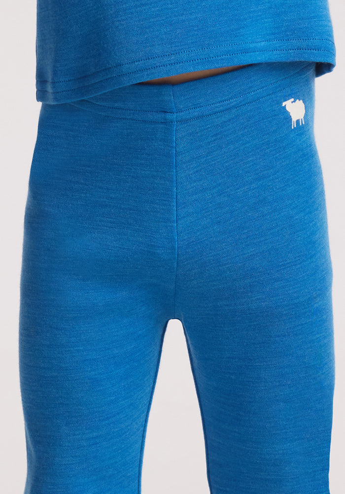 A person wearing Woolx Kids Explorer Base Layer Bottoms in Blue Razz.