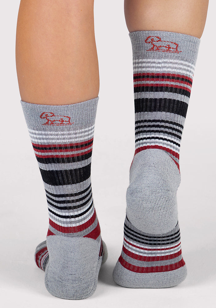 Two feet wear Woolx Womens Everyday Crew Socks in light grey with black, white, and red stripes. These Merino wool socks are moisture-wicking and feature a small red logo near the top on a plain, light backdrop.