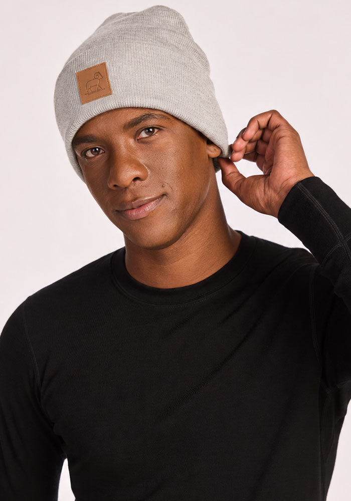 Person in a Woolx Baylor Beanie - Light Ash and black shirt, touching their hat, looking at the camera.