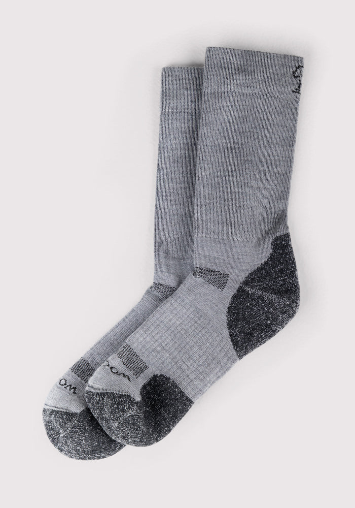 The Woolx Mens Harbor Crew Sock in grey features darker grey heels, toes, and soles. Made from Merino wool, these socks offer superior moisture-wicking and comfort. Displayed flat side by side on a plain white background.