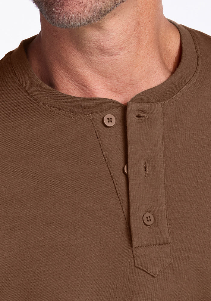 Close-up of a man's lower face, neck, and upper chest wearing the Woolx Jackson Henley - Bourbon Oak, featuring merino wool fabric with moisture-wicking comfort and style—three-button placket with one button unfastened.