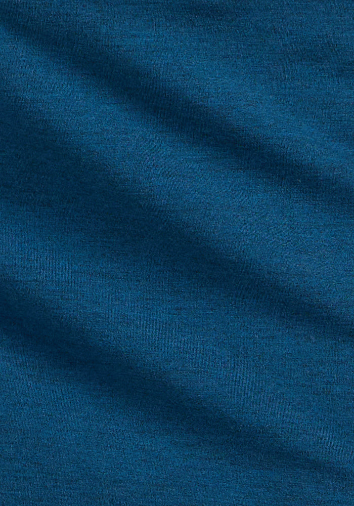 Close-up of the Woolx Audrey Tee in Majolica Blue, showcasing its lightweight, soft fabric with a textured surface and gentle diagonal folds that create subtle shadows and highlights.
