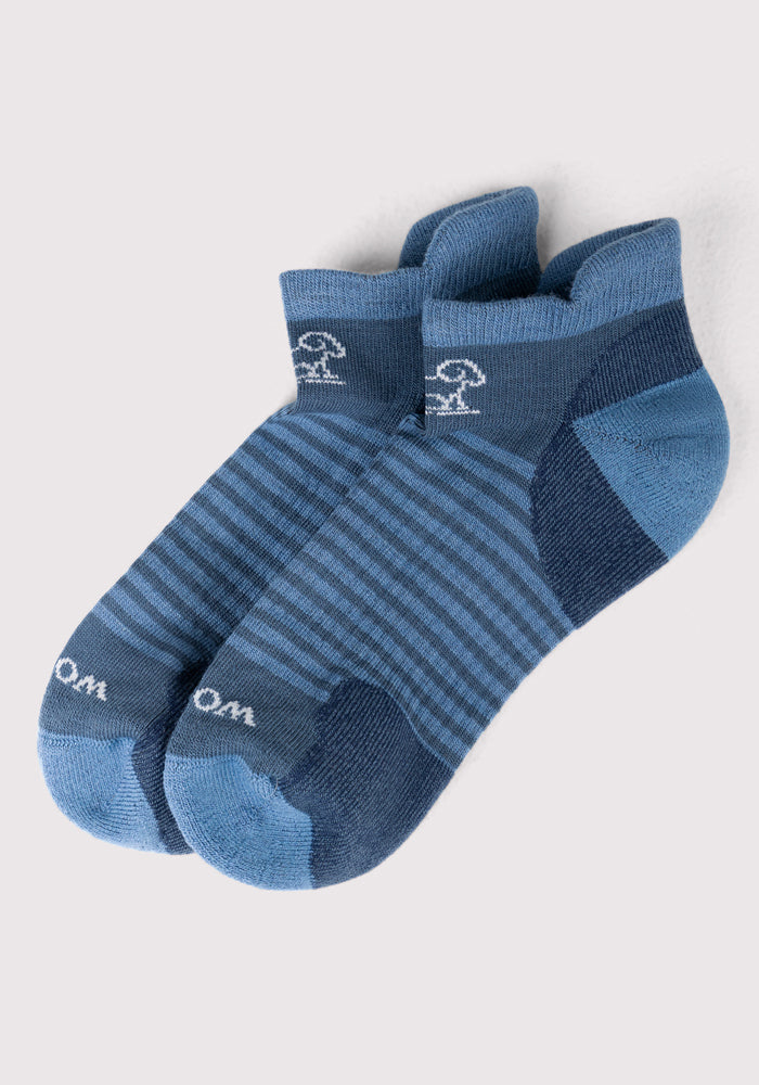 The Womens Amelia No Show Socks by Woolx in Majolica Blue Stripe feature dark blue heels and toes, light blue stripes, and a small white mushroom near the ankle for a discreet fit and soft comfort.