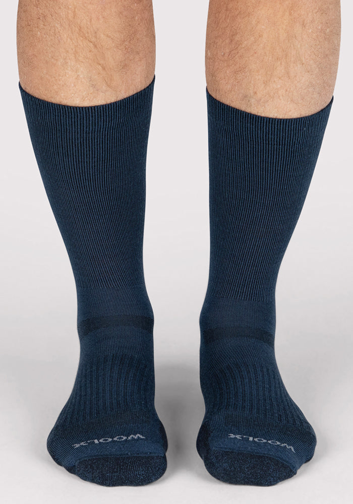 Someone wearing Woolx Mens Harbor Crew Socks in Majolica Blue stands on a light surface with feet together. The ribbed socks, visible on the lower legs, provide comfort and odor resistance.