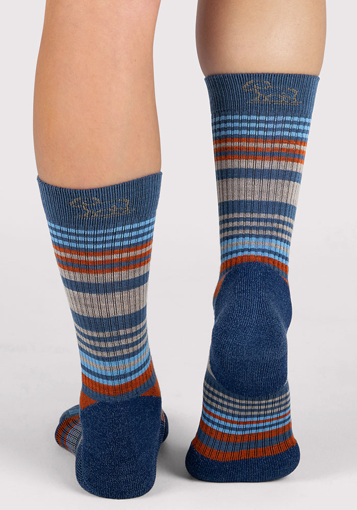 A person's legs wearing Woolx Womens Everyday Crew Socks in Majolica Blue Stripe, featuring moisture-wicking fabric and cushioning.