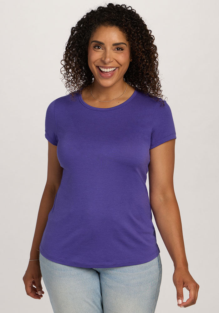 Smiling woman wears Woolx Addie Crew Neck - Berry Indigo and light blue jeans against a plain background. 