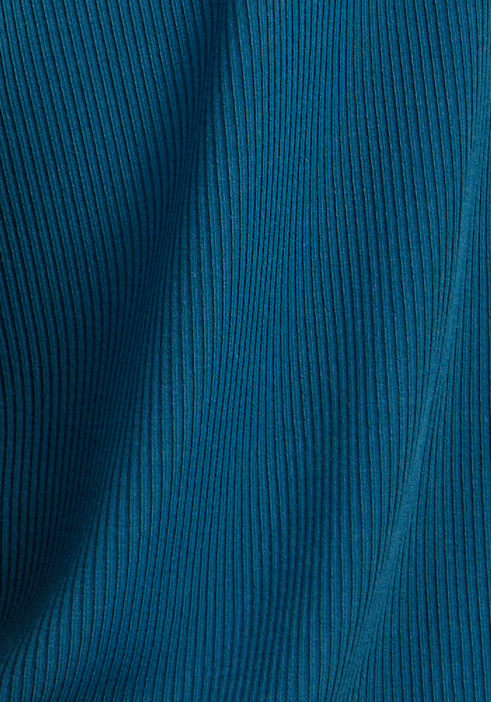 Close-up of Woolx Luca Ribbed Pants in Moroccan Blue, showing vertical textured lines and soft folds that create a wavy, dimensional pattern in the fabric.