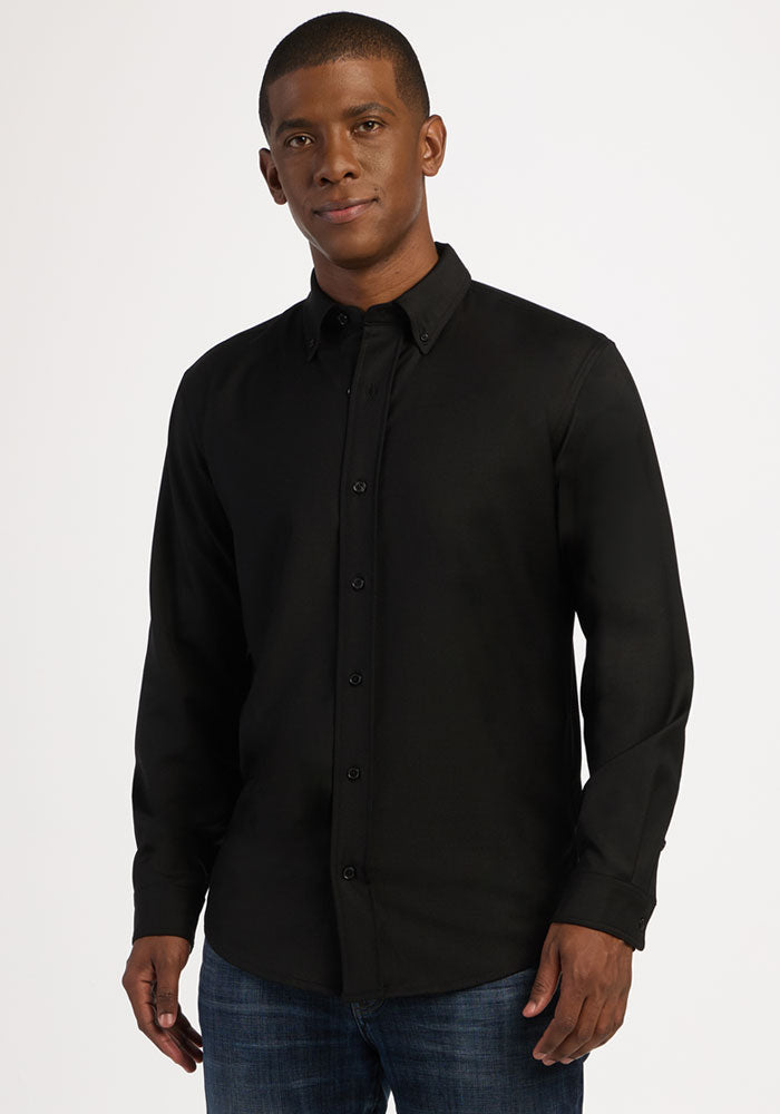 Man wearing a Woolx Nash Button Up - Black and blue jeans, standing against a plain white background.