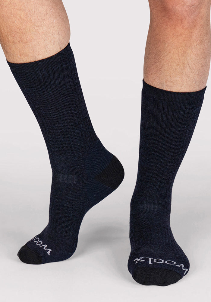 A person wearing Woolx Mens Core Crew Socks in navy, featuring "WOOLX" in white on the toes, stands against a plain light background.