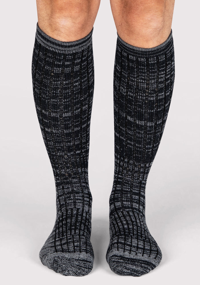 A pair of lower legs wearing Woolx Mens Joey Mid Calf Socks in Dark Navy Marled, standing on a light-colored surface.