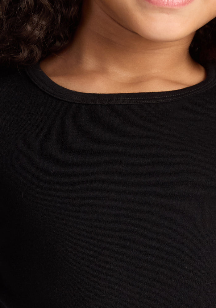 Close-up of a child wearing the Woolx Kids Explorer Base Layer Top in black. The moisture-wicking Merino wool adds comfort, visible as the child smiles slightly; only their lower face, neck, and some curly hair can be seen.