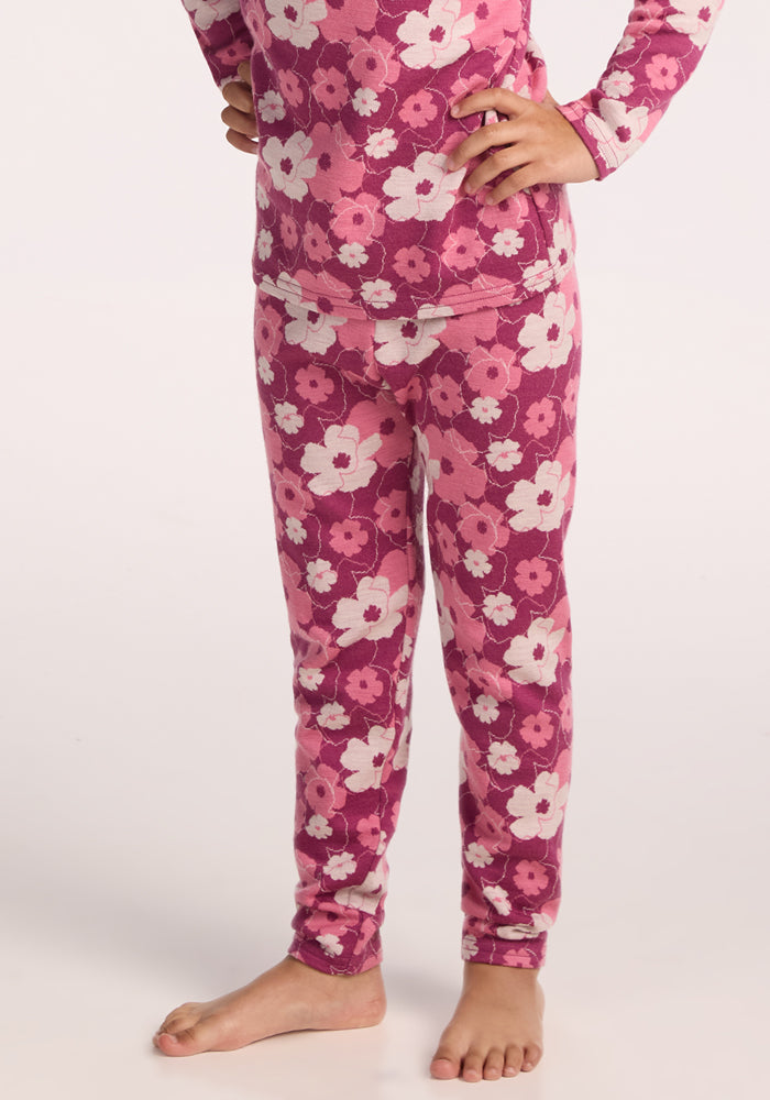 A child, barefoot and cropped at the shoulders, wears Woolx Kids Explorer Base Layer Bottoms - Rosie Posie in a pink floral print—perfect for layering over warm baselayer bottoms.
