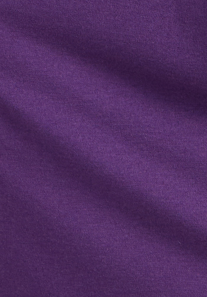 A close-up of the Cassie Dress - Plum Crush by Woolx shows its smooth, purple fabric with subtle folds and soft diagonal shadows highlighting the breathable material.
