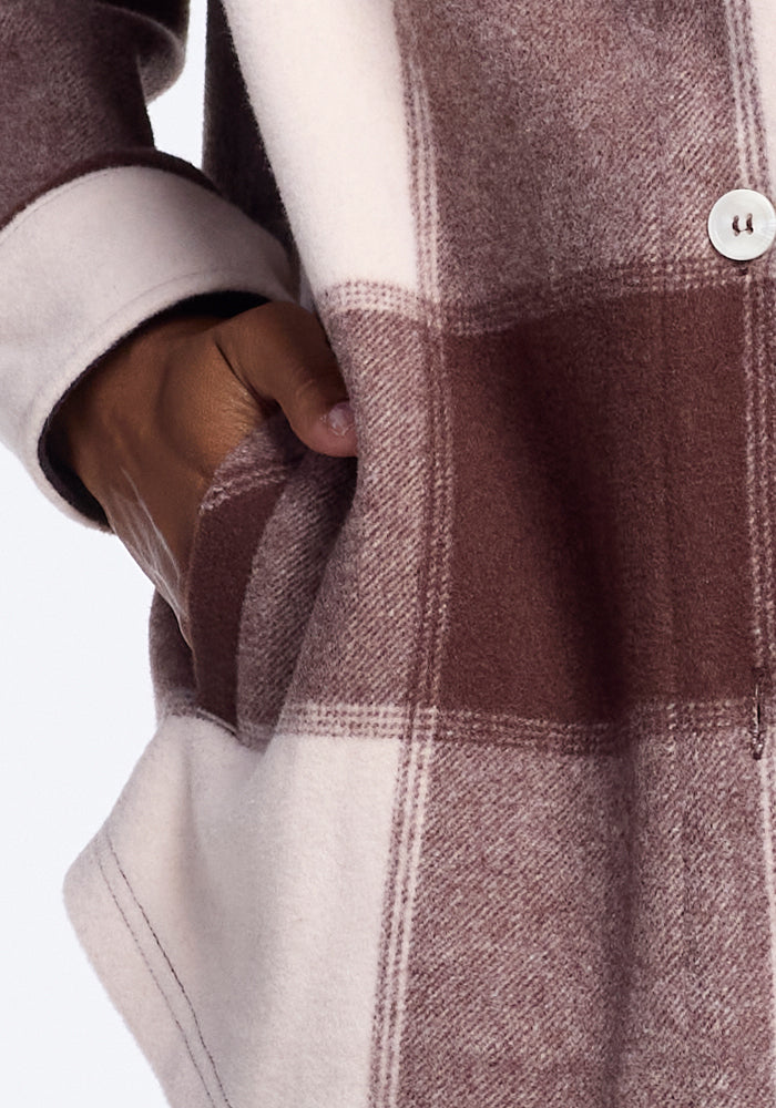 Close-up of a hand in the pocket of a Woolx Sawyer Shacket - Chai Latte Plaid, highlighting the cozy design and soft texture. Buttons are visible on the warm, inviting shacket.