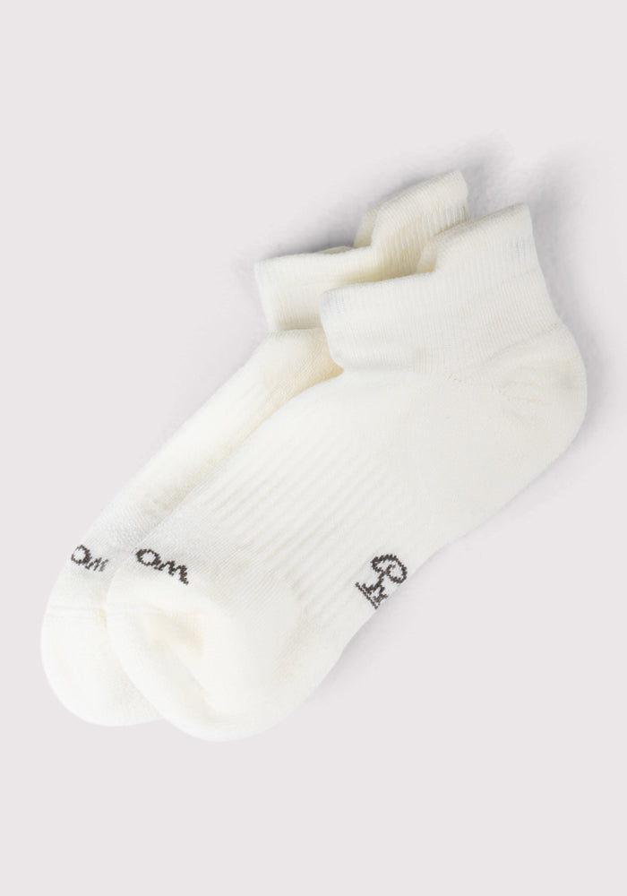 A pair of Woolx Womens Rowan No Show Socks in Polar White, featuring cushioned comfort and small black toe text, are displayed side by side on a light gray background.