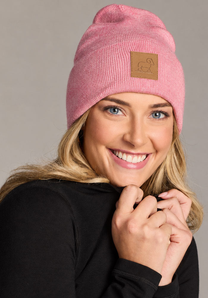 Woman in a Woolx Baylor Beanie - Pinky Promise and black top, smiling at the camera against a plain background.