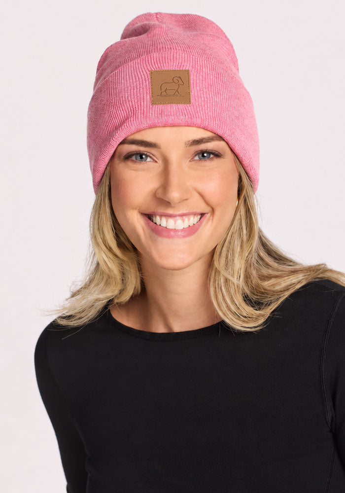 Woman wearing Woolx Baylor Beanie - Pinky Promise and a black shirt, smiling at the camera against a plain background.