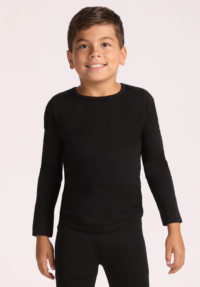A young boy with short brown hair smiles against a light background, wearing the Woolx Kids Explorer Base Layer Top in black and matching pants, both crafted from moisture-wicking fabric. 