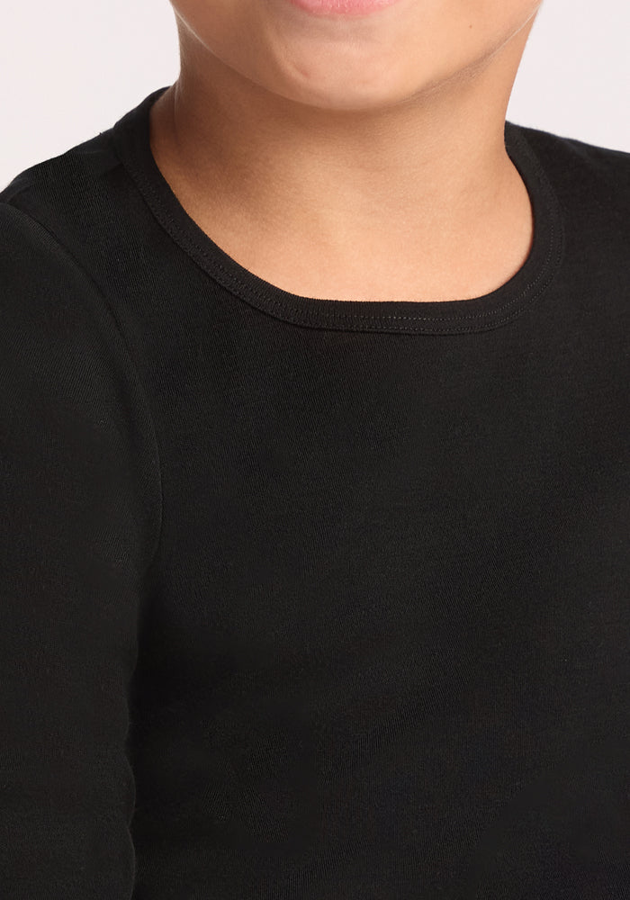 A close-up of a child wearing the Woolx Kids Explorer Base Layer Top in black, showing part of their face and upper chest against a plain, light-colored background.