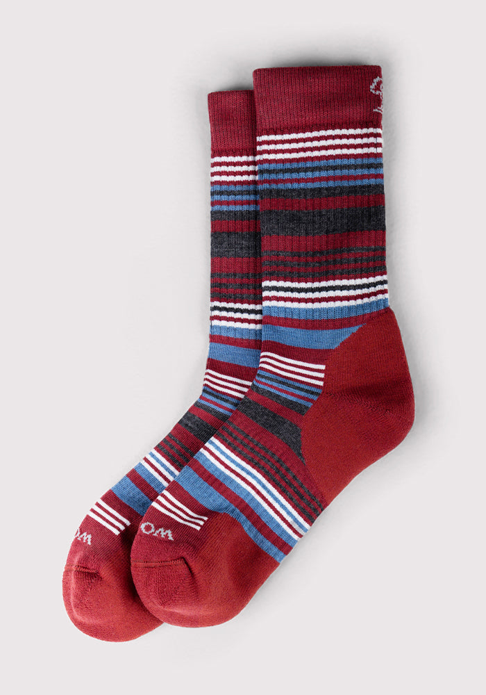 The Woolx Womens Everyday Crew Socks - Rhubarb Stripe offer all-day comfort with a cushioned crew design, a red base, horizontal stripes in white, blue, and black, plus solid red heels, toes, and cuffs.