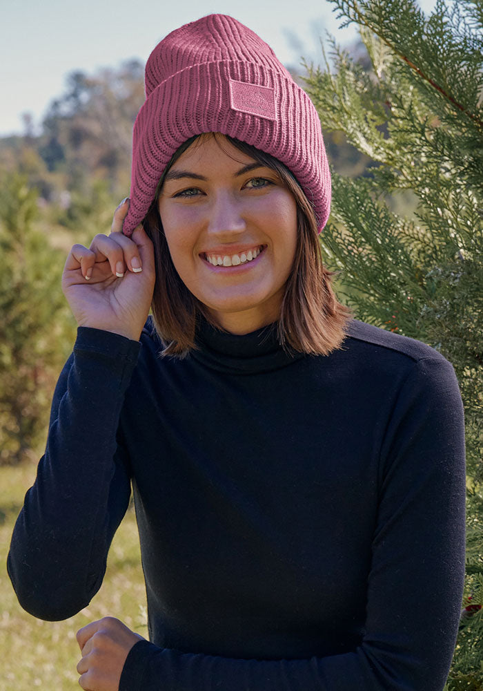 Woman wearing the Woolx Ria Chunky Beanie in Toasted Rose, outdoors near trees on a sunny day.