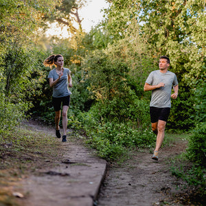 Couple running in woods wearing Woolx.