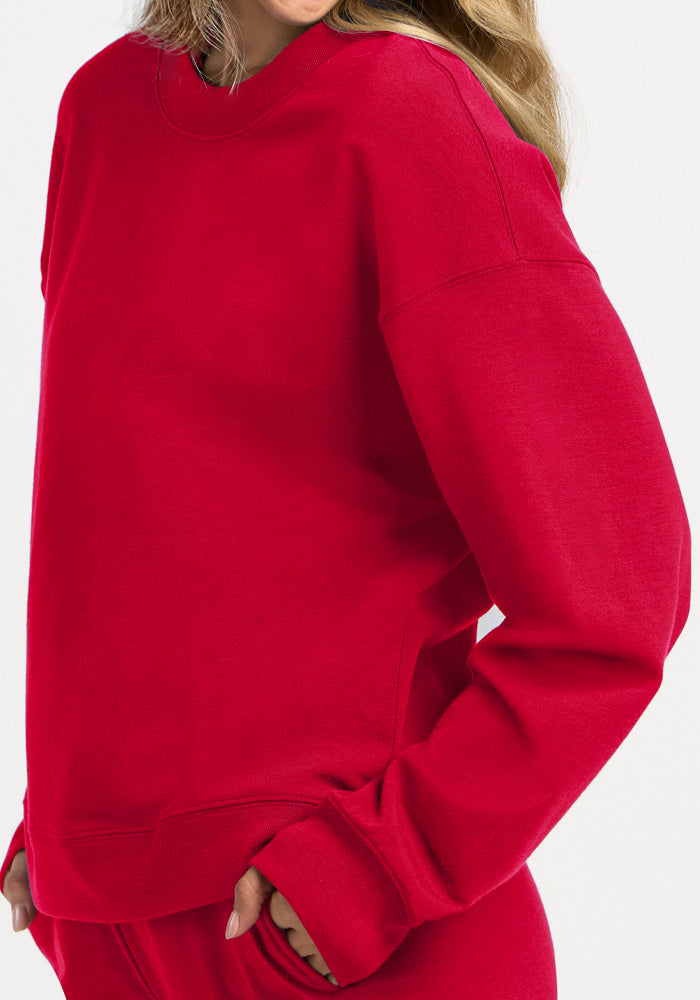 A person wearing a bright red, moisture-wicking Woolx Molly Crewneck - Maraschino Cherry sweatshirt.