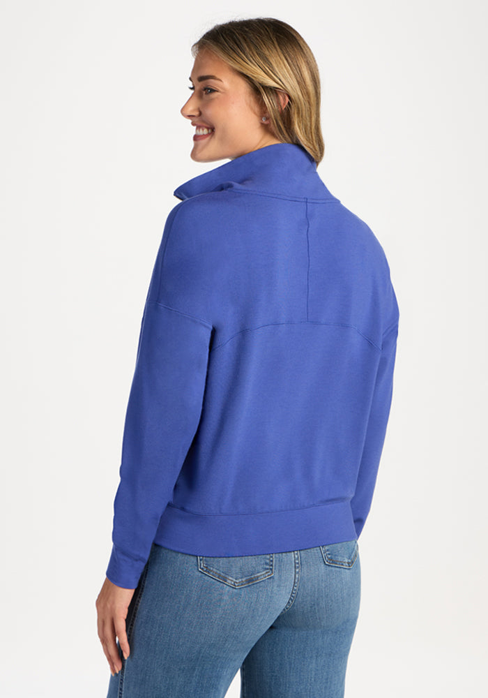 Woman wearing a royal blue Woolx Tori 1/4 Zip, viewed from the side and back.