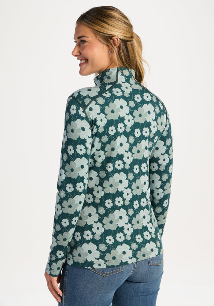 Woman smiling over her shoulder in the Woolx Emi 1/4 Zip - Coastal Wildflower Merino wool base layer and blue jeans.