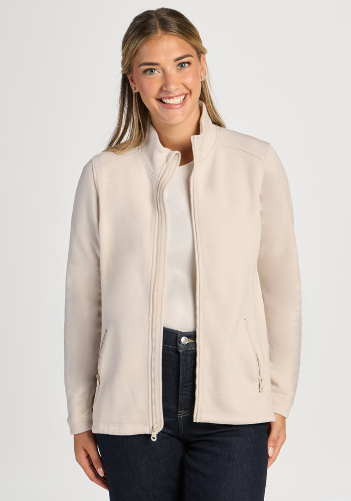 Woman wearing an ultra-heavyweight, cream-colored Woolx Teddy Sweatshirt - Ecru with a mock neck and zippered pockets. 
