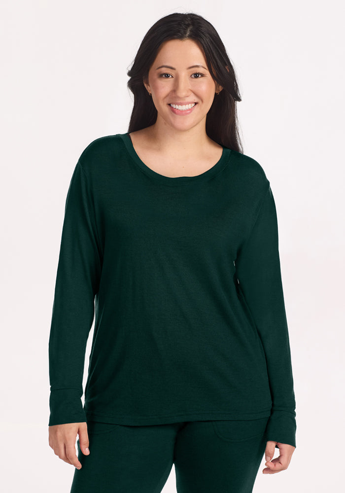 A smiling woman wearing a deep pine Woolx Ashlie Lounge Top made of wrinkle-resistant merino wool. | Sarah is 5'8", wearing a size S