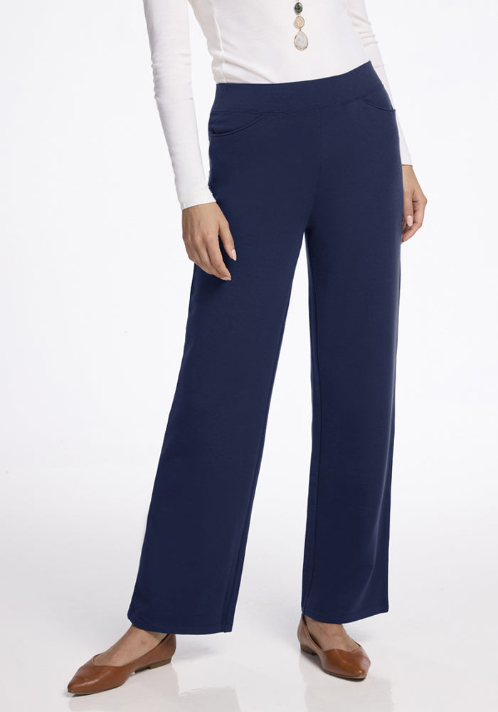 Woman in a white top and Woolx Ellie Wide Leg Pants - Ocean Cavern, with brown flats on a white background. 