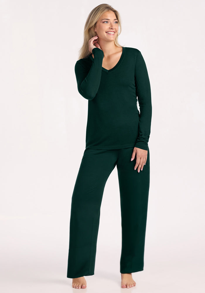 A woman wearing a deep pine Woolx Lily V Neck Lounge Top and matching wide-leg pants.