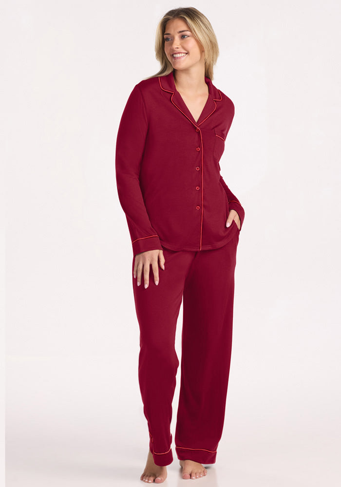 A smiling woman wearing a beet red Harper FeatherTouch® Pajama Set, a merino wool button-down with long sleeves and trim. 