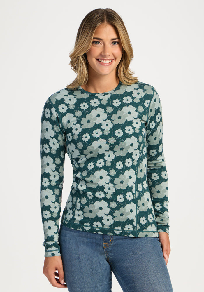 Woman smiling in Woolx Maddie Baselayer Top - Coastal Wildflower, paired with blue jeans against a white background. 