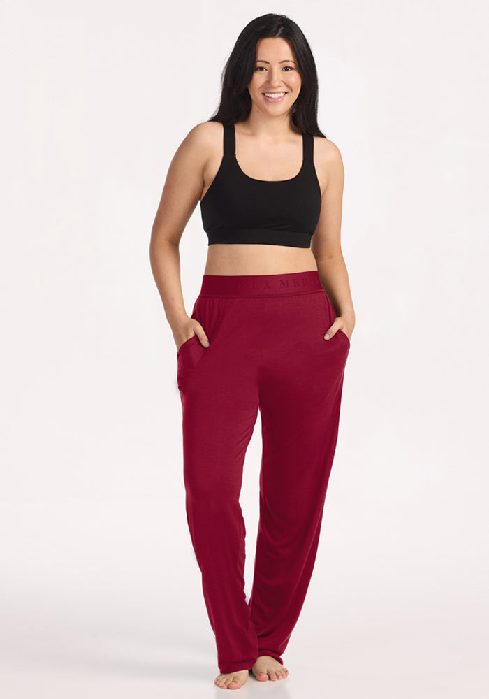 A woman in a black sports bra and beet red Maya Lounge Pants, which are wide-leg pajama pants with pockets.