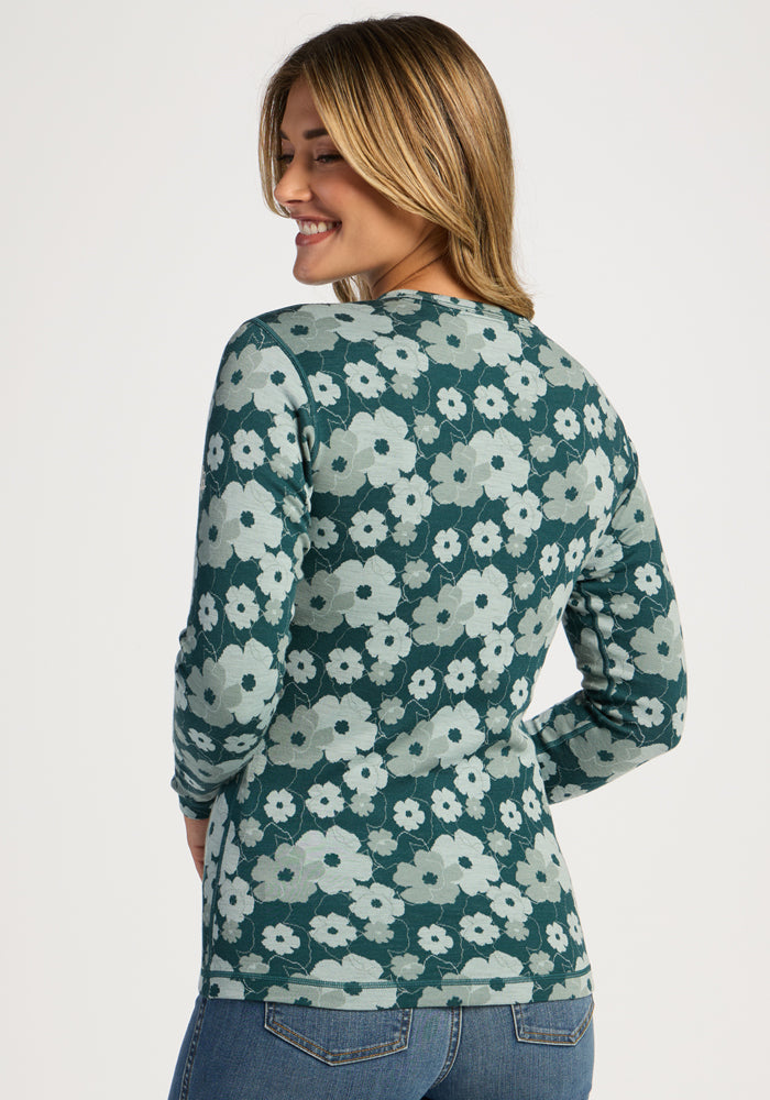Woman smiling, facing away in Woolx Maddie Baselayer Top – Coastal Wildflower print, with blue jeans.
