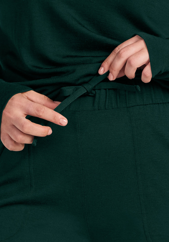 Hands tying the drawstring of moisture-wicking dark green Mary Kate Lounge Pants - Deep Pine.