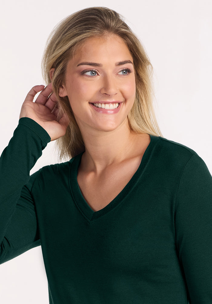 A smiling woman wearing a dark green Woolx Lily V Neck Lounge Top - Deep Pine.