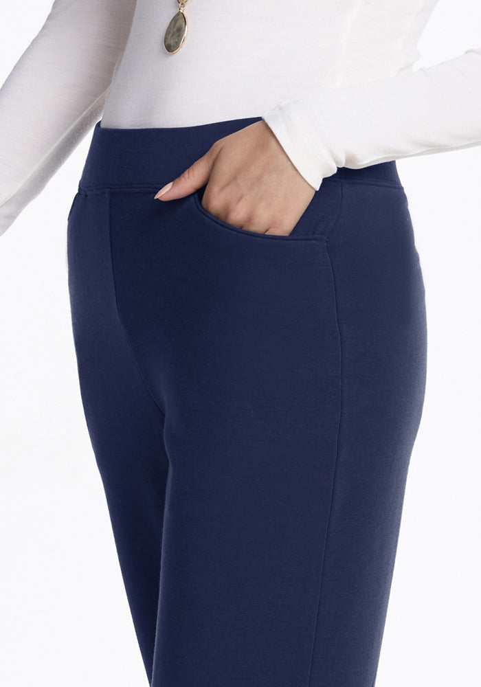 Wearing Woolx Ellie Wide Leg Pants in Ocean Cavern, a person stands with a hand casually tucked into their pocket.