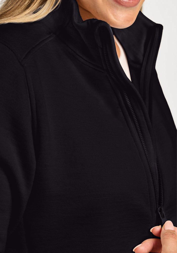 Close-up of a person wearing a black, high-neck zippered Woolx Teddy Sweatshirt made of ultra-heavyweight merino wool.